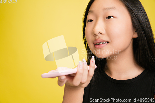 Image of Portrait of young asian girl isolated on yellow studio background