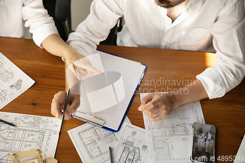 Image of Male architect-engineer presents project of future house for young family.