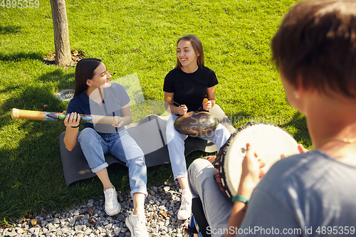 Image of Happy handicapped man on a wheelchair spending time with friends playing live instrumental music outdoors