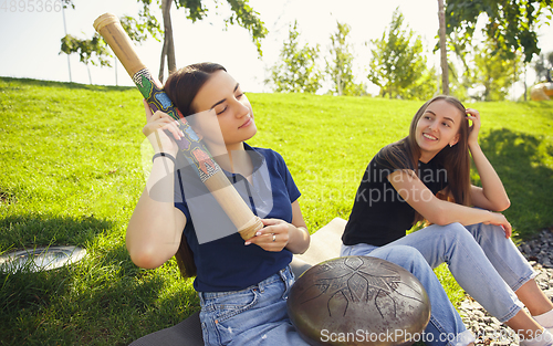 Image of Two girls, friends playing music at summer\'s city street