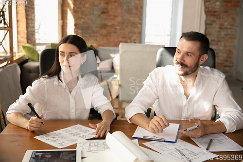 Image of Young family listening to male architect-engineer presents project of future house