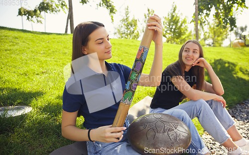 Image of Two girls, friends playing music at summer\'s city street