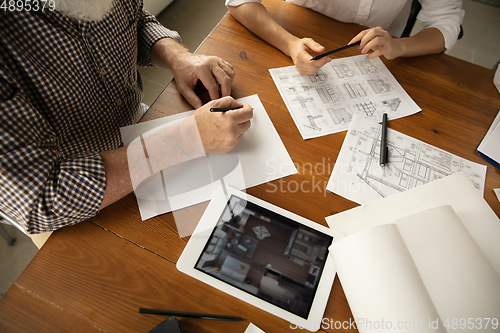 Image of Male architect-engineer presents project of future house for young family.