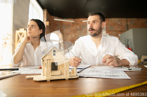 Image of Young family listening to male architect-engineer presents project of future house