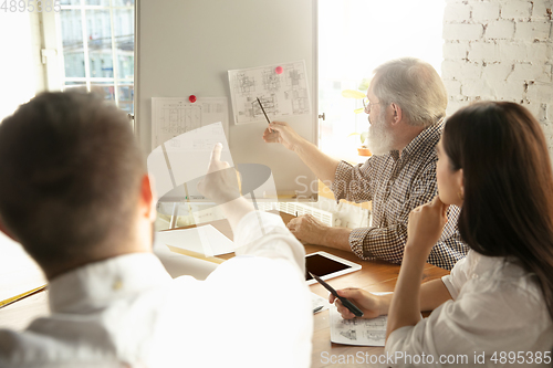 Image of Male architect-engineer presents project of future house for young family.