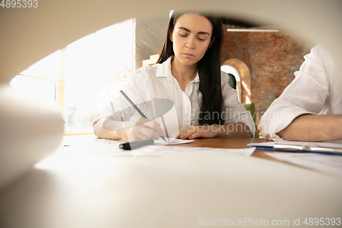 Image of Male architect-engineer presents project of future house for young family.