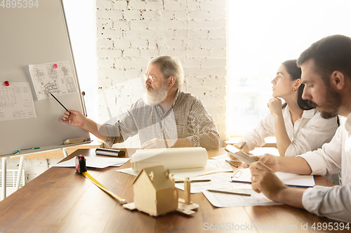 Image of Male architect-engineer presents project of future house for young family.