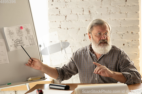 Image of Male architect-engineer presents project of future house for young family.