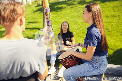 Image of Happy handicapped man on a wheelchair spending time with friends playing live instrumental music outdoors