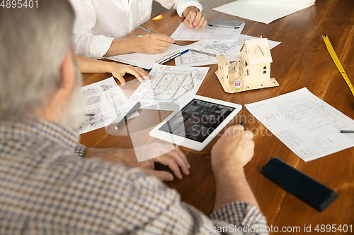 Image of Male architect-engineer presents project of future house for young family.