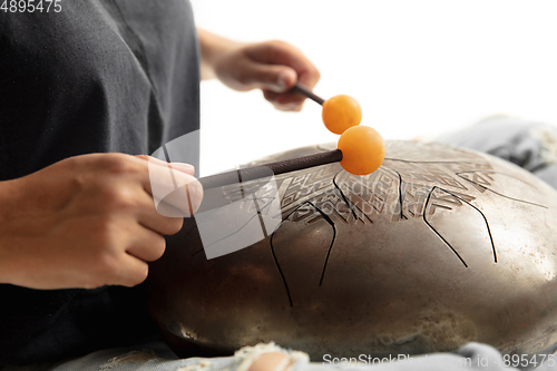 Image of A close up of hands playing the hank drum on white studio background