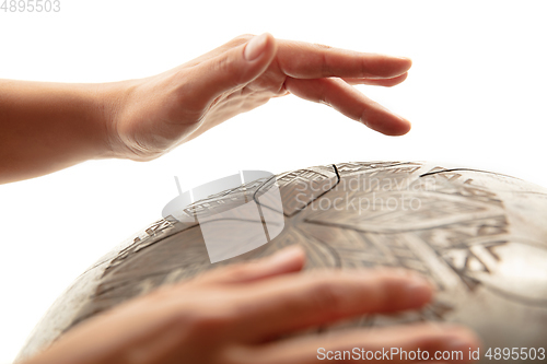 Image of A close up of hands playing the hank drum on white studio background