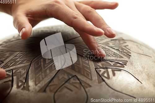 Image of A close up of hands playing the hank drum on white studio background