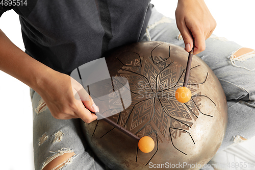 Image of A close up of hands playing the hank drum on white studio background