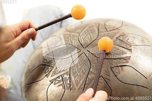 Image of A close up of hands playing the hank drum on white studio background