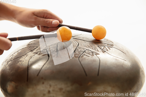 Image of A close up of hands playing the hank drum on white studio background