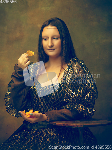 Image of Young woman as Mona Lisa on dark background. Retro style, comparison of eras concept.