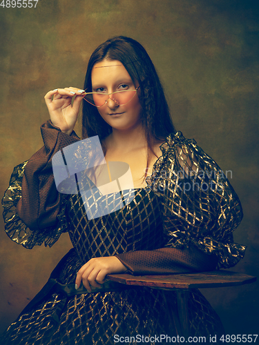 Image of Young woman as Mona Lisa on dark background. Retro style, comparison of eras concept.