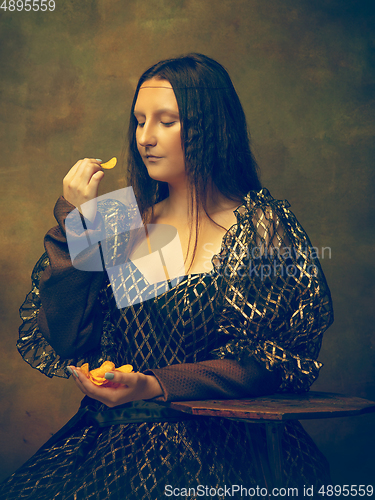 Image of Young woman as Mona Lisa on dark background. Retro style, comparison of eras concept.