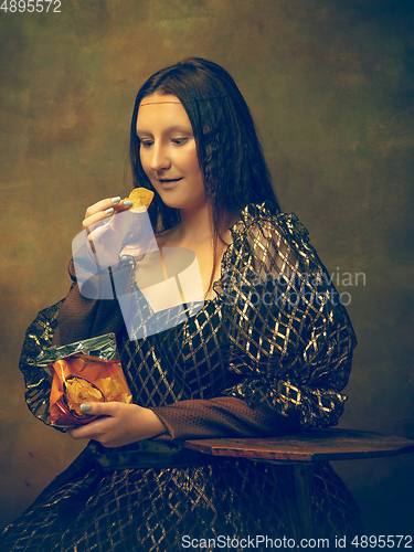 Image of Young woman as Mona Lisa on dark background. Retro style, comparison of eras concept.