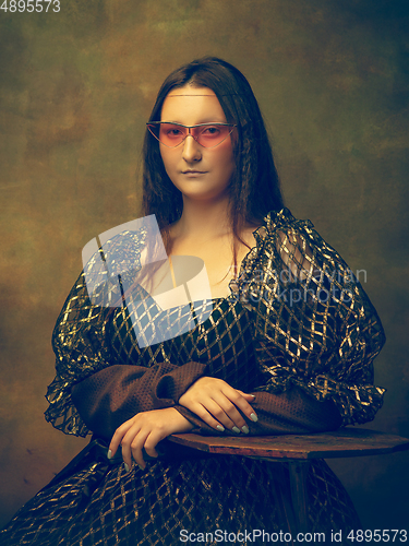 Image of Young woman as Mona Lisa on dark background. Retro style, comparison of eras concept.