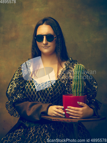 Image of Young woman as Mona Lisa on dark background. Retro style, comparison of eras concept.