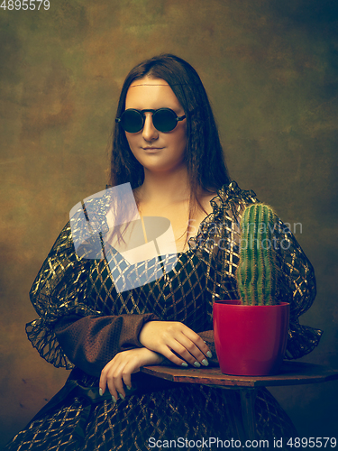 Image of Young woman as Mona Lisa on dark background. Retro style, comparison of eras concept.