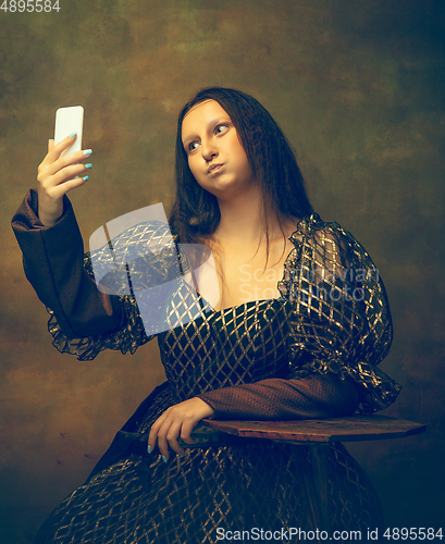 Image of Young woman as Mona Lisa on dark background. Retro style, comparison of eras concept.