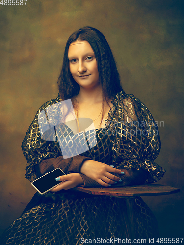 Image of Young woman as Mona Lisa on dark background. Retro style, comparison of eras concept.