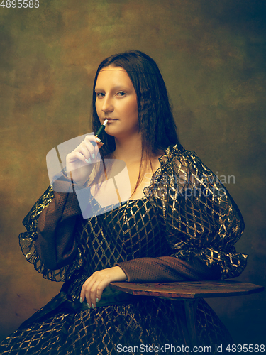 Image of Young woman as Mona Lisa on dark background. Retro style, comparison of eras concept.