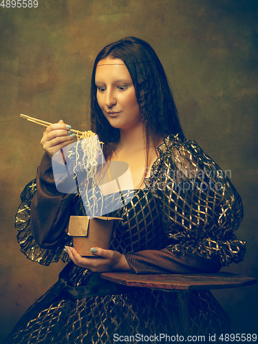 Image of Young woman as Mona Lisa on dark background. Retro style, comparison of eras concept.