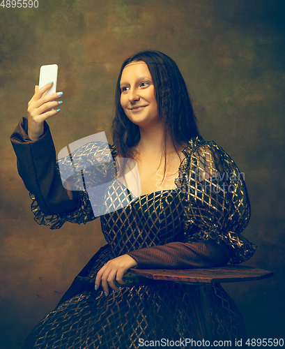 Image of Young woman as Mona Lisa on dark background. Retro style, comparison of eras concept.