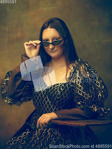 Image of Young woman as Mona Lisa on dark background. Retro style, comparison of eras concept.