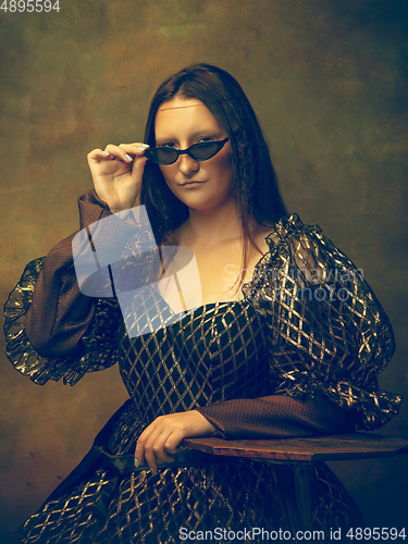 Image of Young woman as Mona Lisa on dark background. Retro style, comparison of eras concept.
