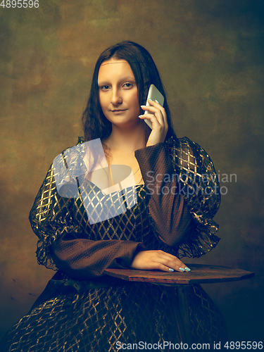 Image of Young woman as Mona Lisa on dark background. Retro style, comparison of eras concept.