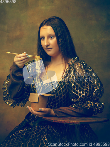 Image of Young woman as Mona Lisa on dark background. Retro style, comparison of eras concept.