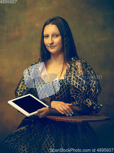 Image of Young woman as Mona Lisa on dark background. Retro style, comparison of eras concept.