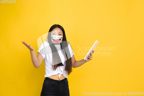 Image of Portrait of young girl with emotion on her protective face mask isolated on studio background. Beautiful female model, funny expression