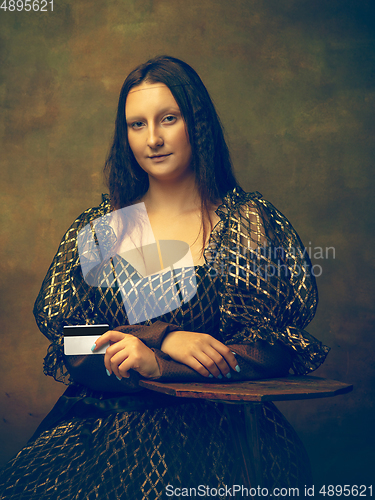 Image of Young woman as Mona Lisa on dark background. Retro style, comparison of eras concept.