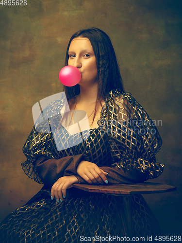 Image of Young woman as Mona Lisa on dark background. Retro style, comparison of eras concept.