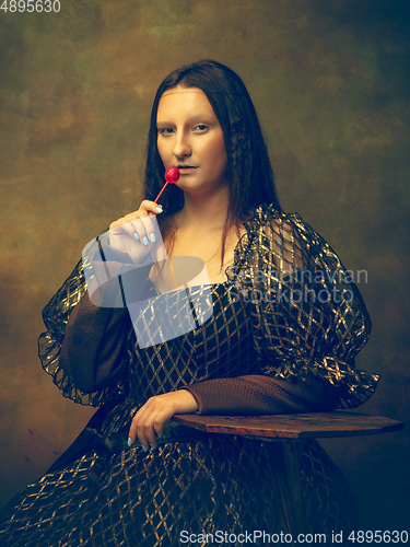 Image of Young woman as Mona Lisa on dark background. Retro style, comparison of eras concept.