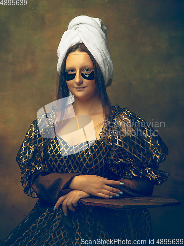 Image of Young woman as Mona Lisa on dark background. Retro style, comparison of eras concept.