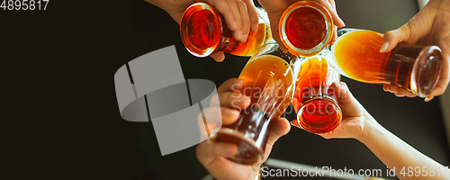 Image of Hands of young friends, colleagues during beer drinking, having fun, laughting and celebrating together. Flyer with copyspace