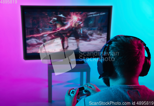 Image of Back view shot of professional gamer playing online video game on his personal computer.