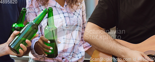 Image of Hands of young friends, colleagues during beer drinking, having fun, laughting and celebrating together. Flyer with copyspace