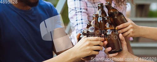 Image of Hands of young friends, colleagues during beer drinking, having fun, laughting and celebrating together. Flyer with copyspace