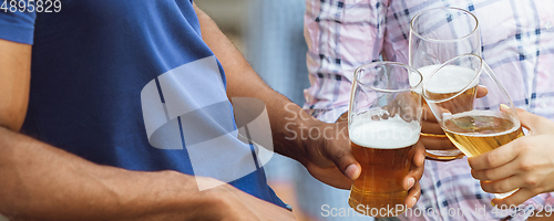 Image of Hands of young friends, colleagues during beer drinking, having fun, laughting and celebrating together. Flyer with copyspace