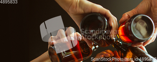 Image of Hands of young friends, colleagues during beer drinking, having fun, laughting and celebrating together. Flyer with copyspace