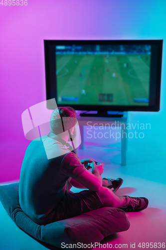 Image of Back view shot of professional gamer playing online video game on his personal computer.