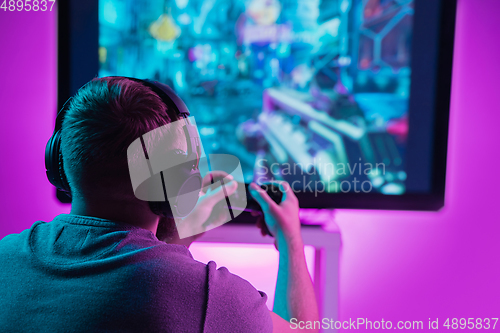 Image of Back view shot of professional gamer playing online video game on his personal computer.